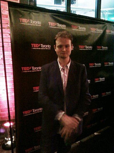 Kyle Clements Poses for a photo in front of the TEDxToronto banner.